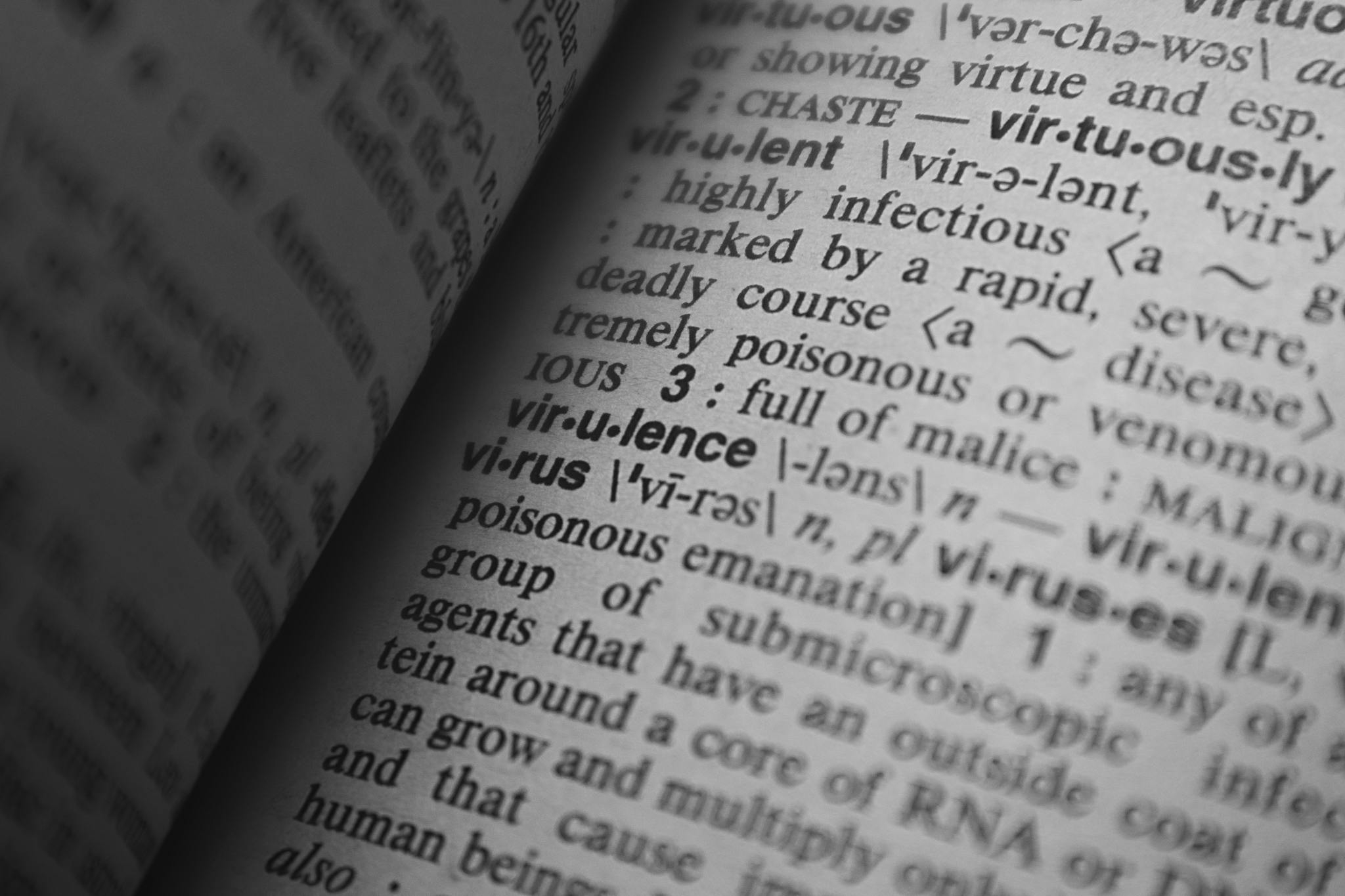 Black and white close-up of a dictionary page showing the definition of 'virus.'